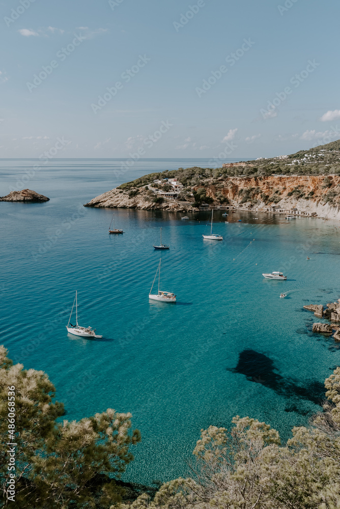 A tranquil scene of beautiful landscape in Ibiza overlooking turquoise waters and white sand beach. 