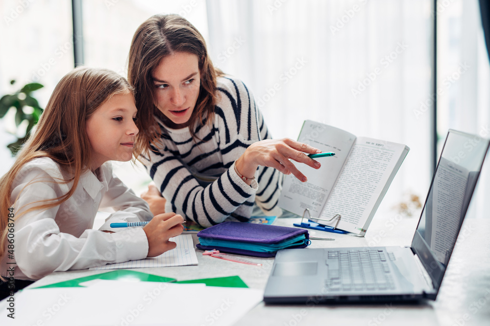 Mother and daughter watching a textbook together. Mother and daughter watching a textbook together.