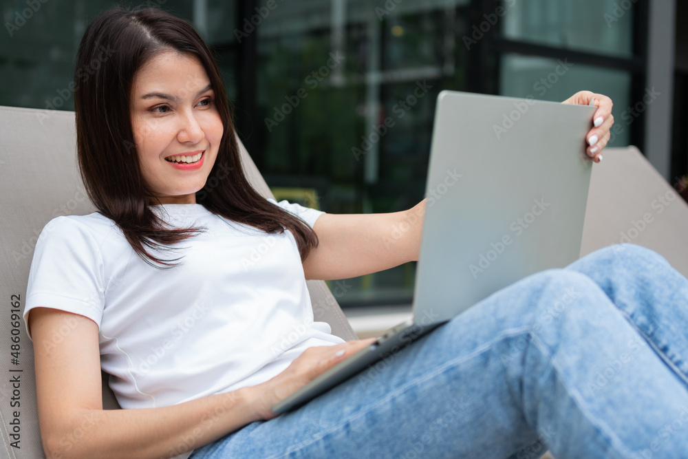 Happy young entrepreneur woman sitting on tanning bed beside pool and using laptop computer for remote online working digital, online business project in quiet yard of resort house, Work on vacation Happy young entrepreneur woman sitting on tanning bed beside pool and using laptop computer for remote online working digital, online business project in quiet yard of resort house, Work on vacation