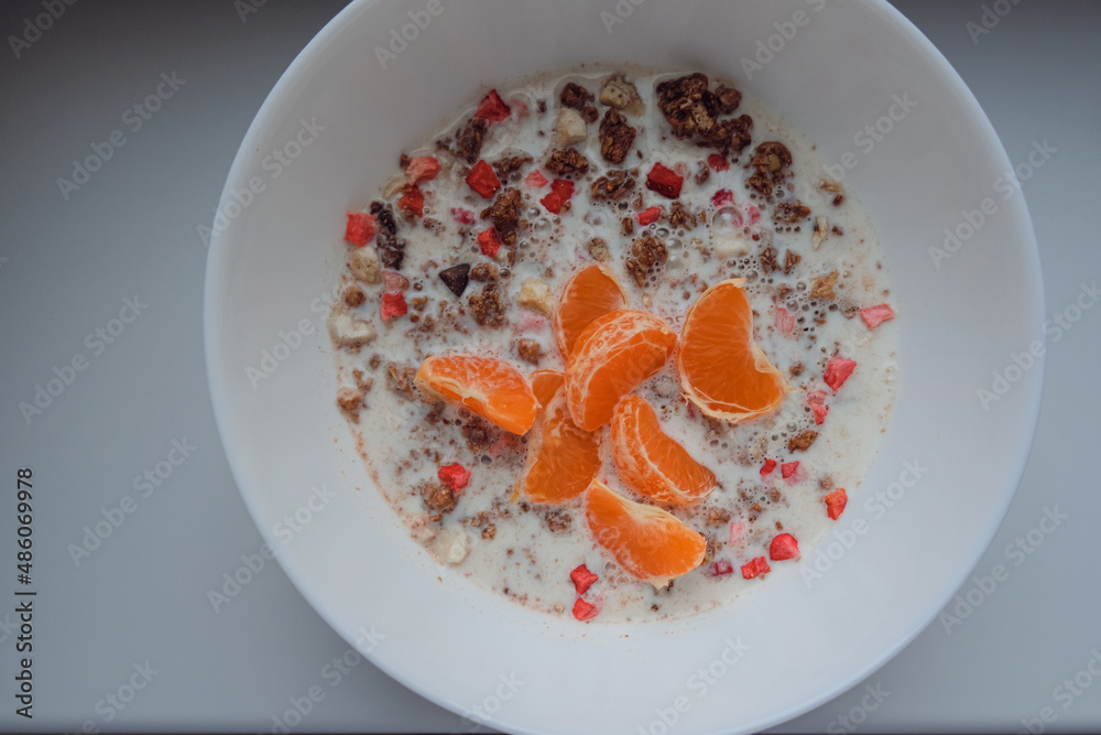 granola with oat milk, strawberry and tangerine for healthy breakfast. Morning breakfast closeup. granola with oat milk, strawberry and tangerine for healthy breakfast. Morning breakfast closeup.