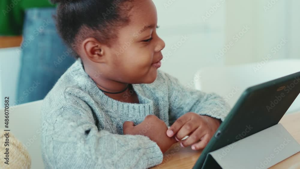 Positive African little girl watching something at the tablet at home Positive African little girl watching something at the tablet at home