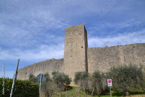 castle wall in Siena, Italy, with brown bricks and trees and blue sky in the background, in beautiful day