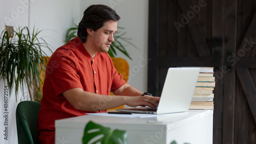 Young man working with laptop computer at home office