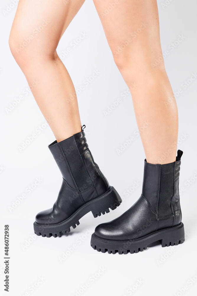 Women's black spring boots made of genuine leather are dressed on bare feet