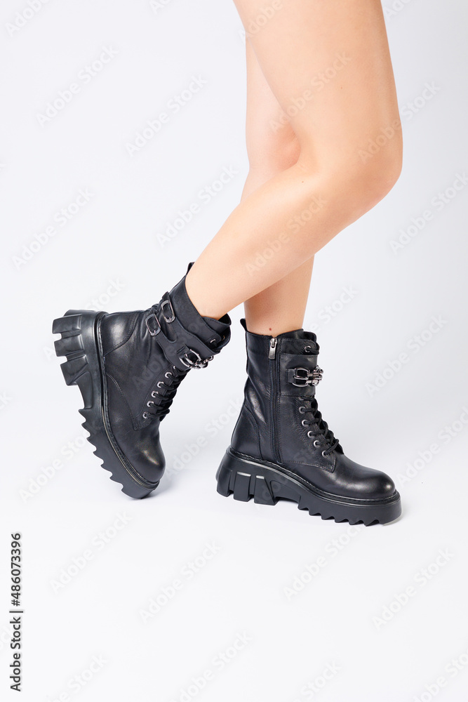 Legs of a woman in black leather boots from a new collection on a white background, legs of a girl in fashionable leather boots spring 2022. Legs of a woman in black leather boots from a new collection on a white background, legs of a girl in fashionable leather boots spring 2022.
