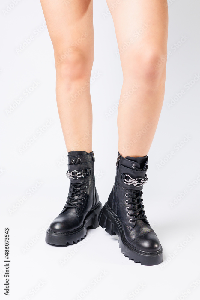 Legs of a woman in black leather boots from a new collection on a white background, legs of a girl in fashionable leather boots spring 2022. Legs of a woman in black leather boots from a new collection on a white background, legs of a girl in fashionable leather boots spring 2022.