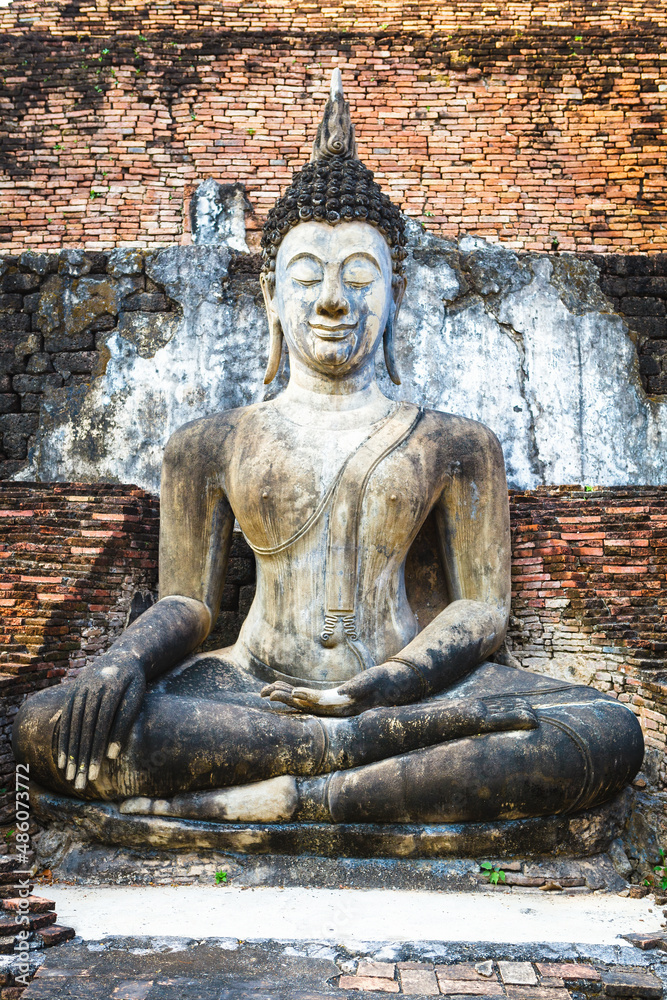 Obraz premium Sukhothai historical park, Buddha statue in Wat Mahathat ruins. One of most beautiful and worth seen place in Thailand. Popular travel destination while visiting southeast Asia.