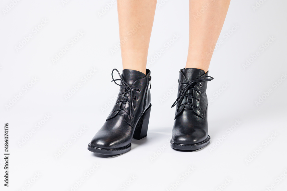 Fashionable woman in stylish leather shoes with heels. Female beautiful legs with fashionable boots in the studio on an isolated white background Fashionable woman in stylish leather shoes with heels. Female beautiful legs with fashionable boots in the studio on an isolated white background
