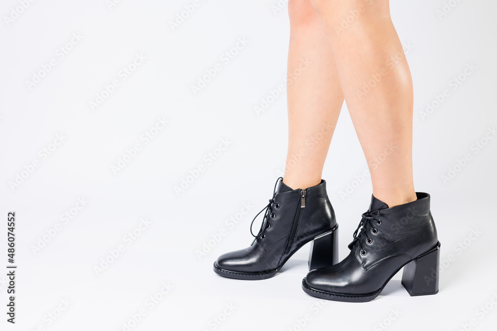 Fashionable woman in stylish leather shoes with heels. Female beautiful legs with fashionable boots in the studio on an isolated white background Fashionable woman in stylish leather shoes with heels. Female beautiful legs with fashionable boots in the studio on an isolated white background