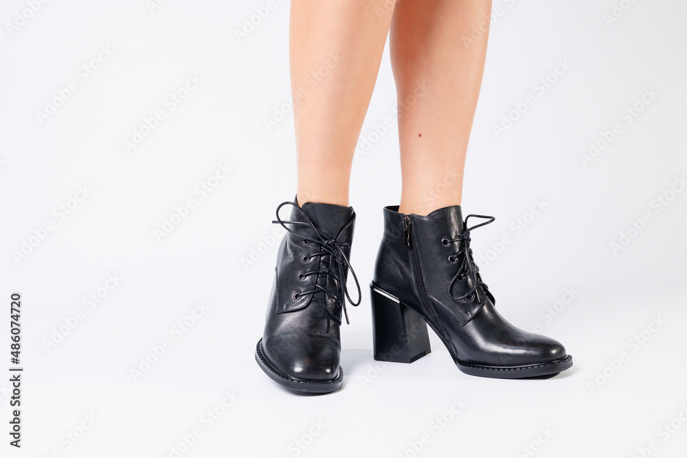 Fashionable woman in stylish leather shoes with heels. Female beautiful legs with fashionable boots in the studio on an isolated white background Fashionable woman in stylish leather shoes with heels. Female beautiful legs with fashionable boots in the studio on an isolated white background