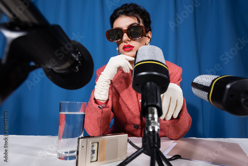 microphones near glass of water, dictaphone and vintage style woman on blue background photo