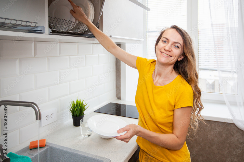 apartments. A woman washes dishes in the kitchen apartments. A woman washes dishes in the kitchen