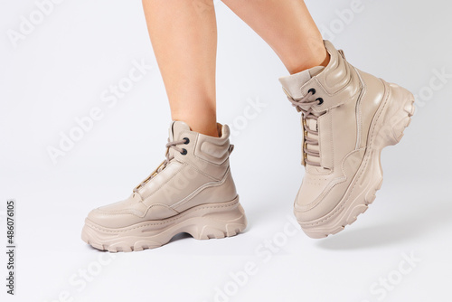 Female legs in beige leather shoes from the new collection on a white background female legs in fashionable shoes made of eco-leather spring 2022.