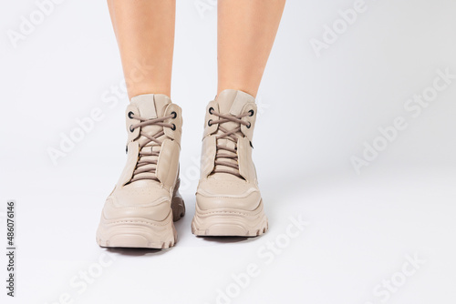 Female legs in beige leather shoes from the new collection on a white background female legs in fashionable shoes made of eco-leather spring 2022. © Дмитрий Ткачук