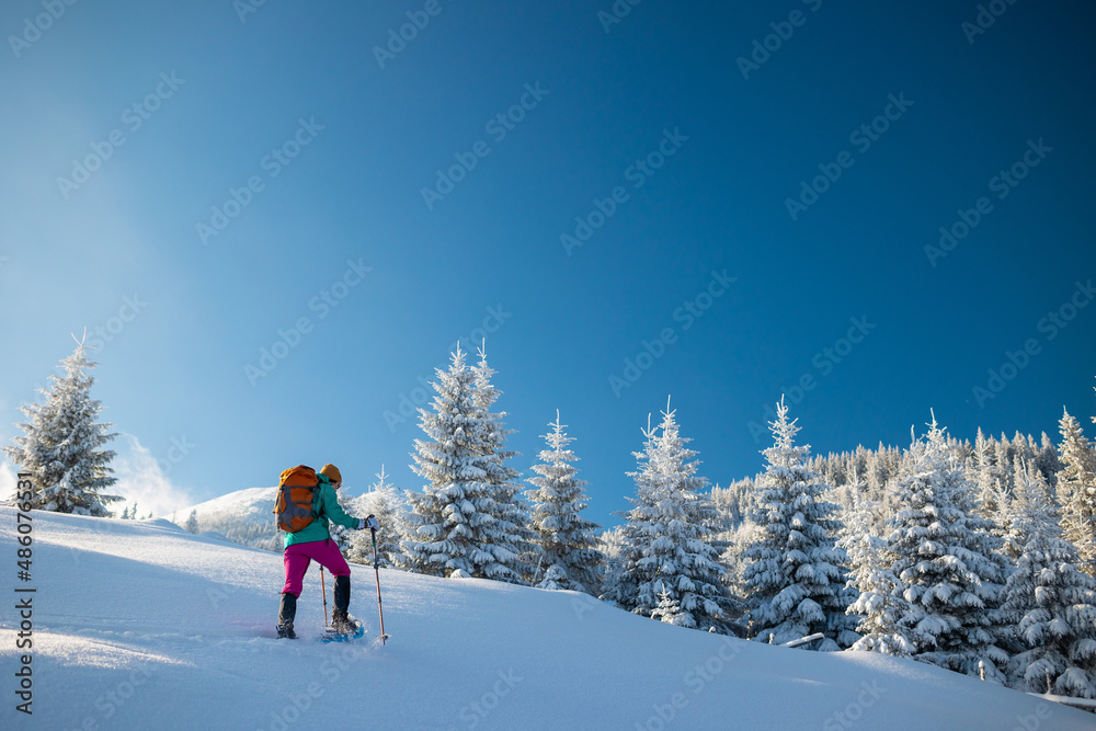 A woman walks in snowshoes in winter trekking