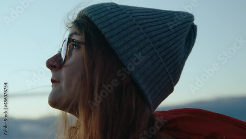 Authentic and cinematic portrait of real young woman stand on mountain top and look at sky, enjoy nature and quiet. Concept mindfulness and peace, new generation of conscious and responsible consumers photo