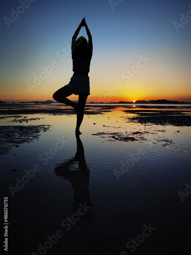 Silhouette of the yoga on the beach,posing in front of the sunset on the beach.