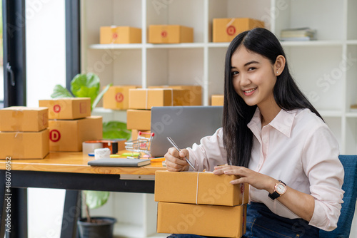 Starting a Small Business, SME, Independent Entrepreneur Asian woman working at home with cardboard boxes, smartphones, laptops, online, marketing, packaging, transportation, SME, e-commerce concept. © ArLawKa