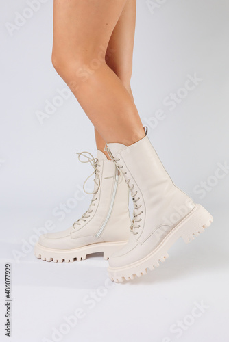 Woman's legs in a collection of fashionable leather white shoes on a white background, spring collection of women's shoes