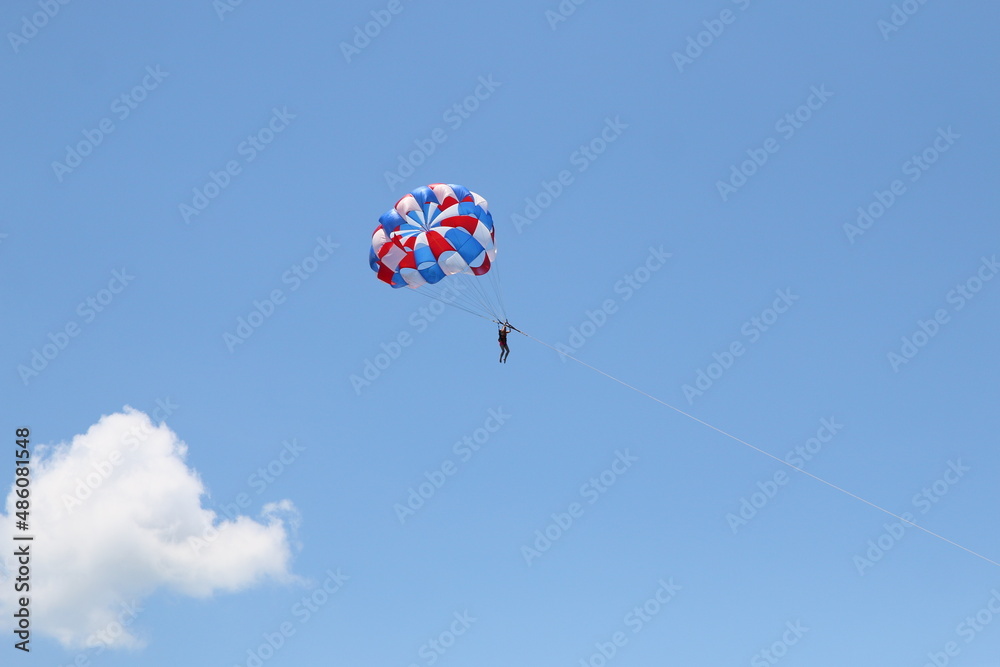 A woman is gliding using a parachute on the background of cloudy blue sky. A woman is gliding using a parachute on the background of cloudy blue sky.