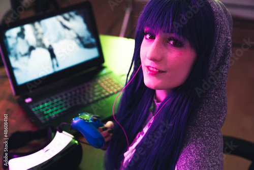 Young brunette in a hoodie uses gamepad and encourages to play with her medium close-up shot. High quality photo
