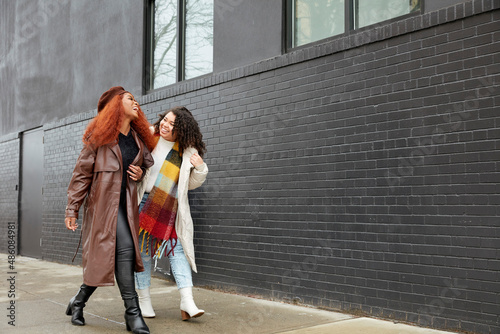 Canvas Print Smiling women walking alongside black building