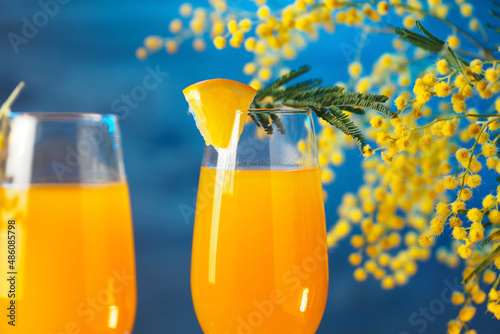 mimosa drink and flowers on a blue background. Cocktail for March 8