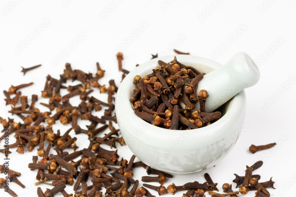 Cloves in white mortar with pestle isolated on white background. Herbal cloves have a fragrant and spicy flavor. Cloves in white mortar with pestle isolated on white background. Herbal cloves have a fragrant and spicy flavor.