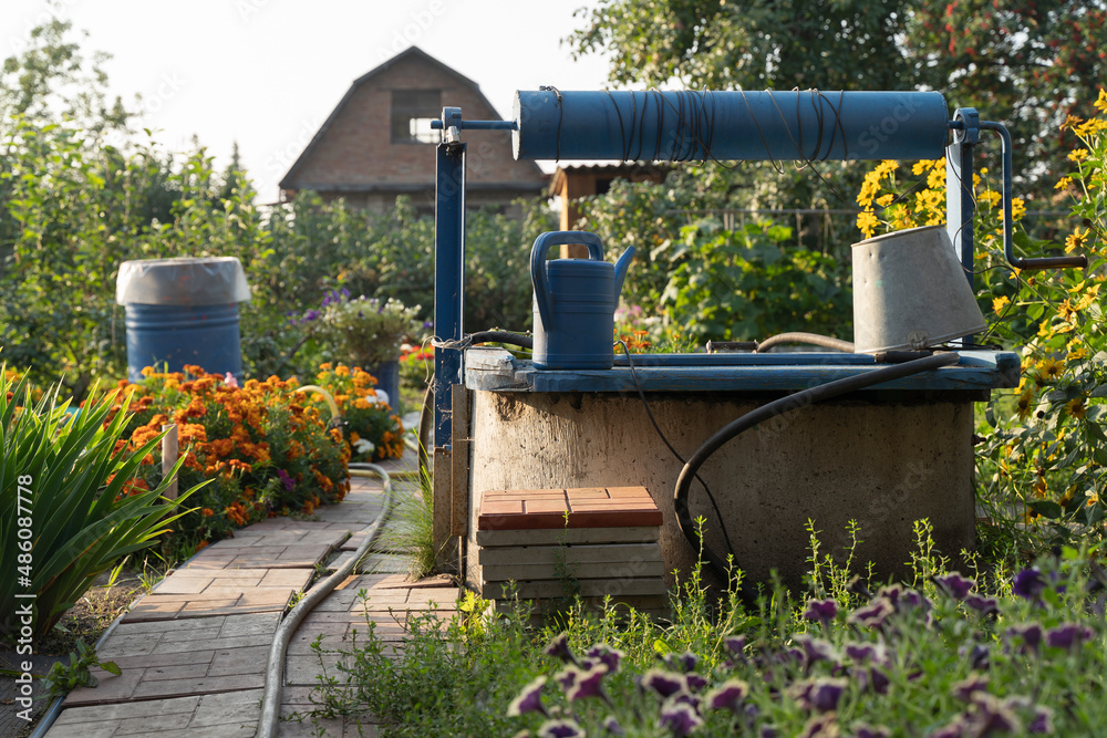 Blue Ancient artesian well from an iron tank in the garden. well in the garden, saving water in times of drought Blue Ancient artesian well from an iron tank in the garden. well in the garden, saving water in times of drought