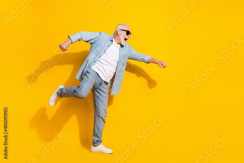 Full length body size view of attractive cheerful motivated grey-haired man having fun isolated over shine yellow color background