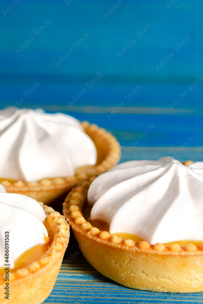 Lemon tartlets, Homemade shortbread mini tart cakes with lemon curd and whipped cream, blue background Lemon tartlets, Homemade shortbread mini tart cakes with lemon curd and whipped cream, blue background
