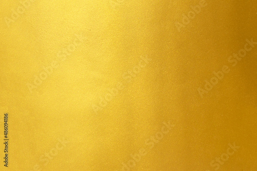 Gold wall texture background. Yellow shiny gold foil paint on wall sheet with gloss light reflection, photo