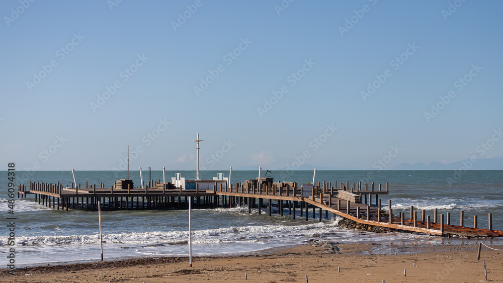 Fototapeta premium Beautiful sea panton and beach. A large wooden pier is on the sandy beach of the resort. Beautiful view of the tropical coast with a long pantone. Landscape of the sea coast