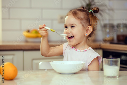 Happy little girl child 2-3 years old eats healthy food at home or in kindergarten.