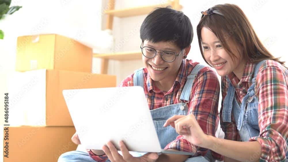 Young asian couple smile and relaxing in new apartment, looking at laptop screen. Joyful woman sitting use computer with husband, enjoying weekend time together. network internet of things Young asian couple smile and relaxing in new apartment, looking at laptop screen. Joyful woman sitting use computer with husband, enjoying weekend time together. network internet of things