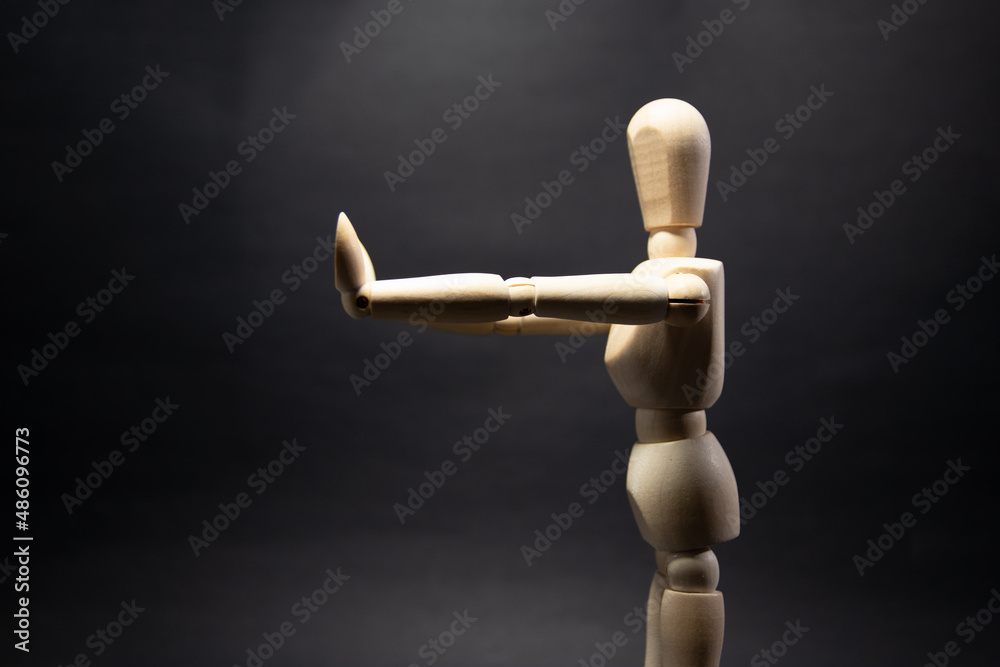 The wooden mannequin raising arm and stopping, pulling. on a black background The wooden mannequin raising arm and stopping, pulling. on a black background