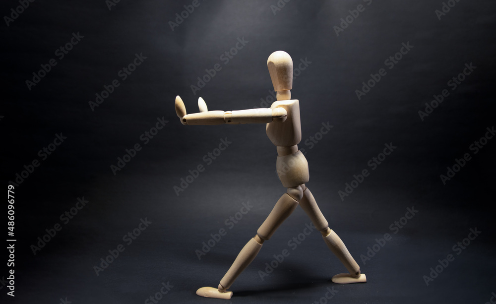 The wooden mannequin raising arm and stopping,pulling. on a black background