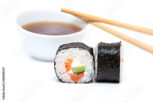 Sushi roll with salmon isolated on a white background with Japanese chopsticks and sauce in the thicket