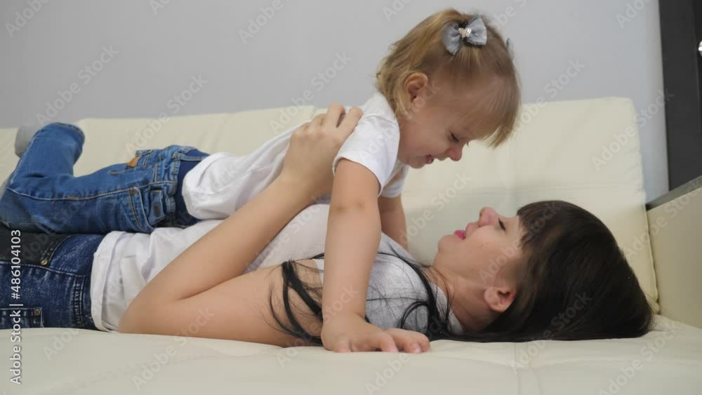 happy family concept .woman playing with a little girl on the bed. lifestyle Mother lies on her back and holds her daughter on her feet. mom kisses daughter laughing teamwork