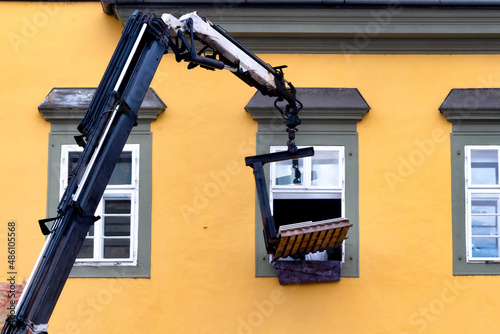 Building material is delivered by crane through the window of a residential building