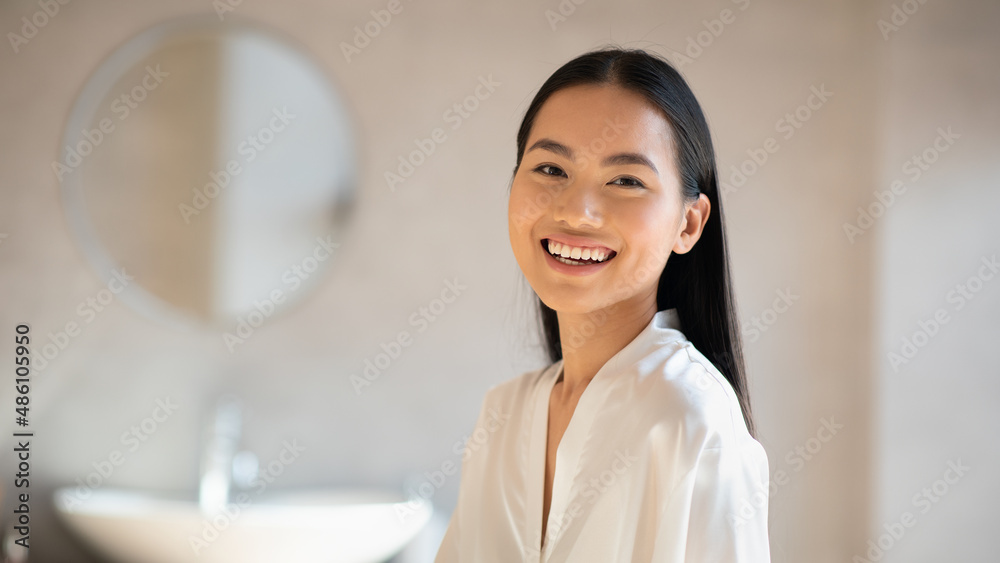 Cheerful pretty chinese lady smiling at camera, bathroom interior Cheerful pretty chinese lady smiling at camera, bathroom interior