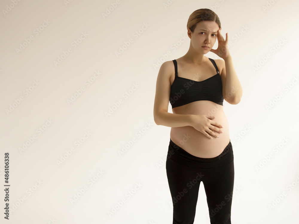 Pregnant woman with a headache and pain. Young pregnant woman with headache and backache copy space. Pregnancy symptoms, healthcare concept Pregnant woman with a headache and pain. Young pregnant woman with headache and backache copy space. Pregnancy symptoms, healthcare concept
