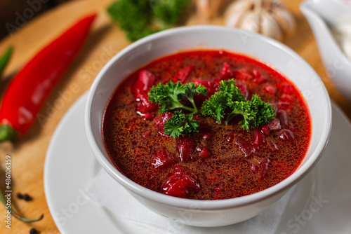 Russian borscht in white dishes on a wooden background in a cafe