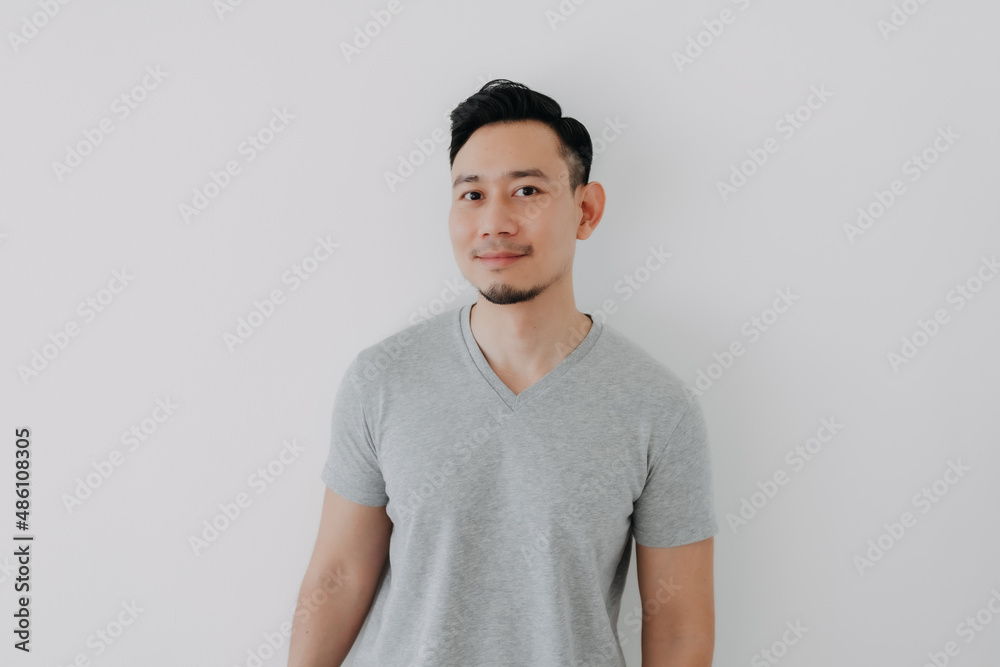 Portrait of Happy Asian man wear grey t-shirt stand isolated on white wall. Portrait of Happy Asian man wear grey t-shirt stand isolated on white wall.