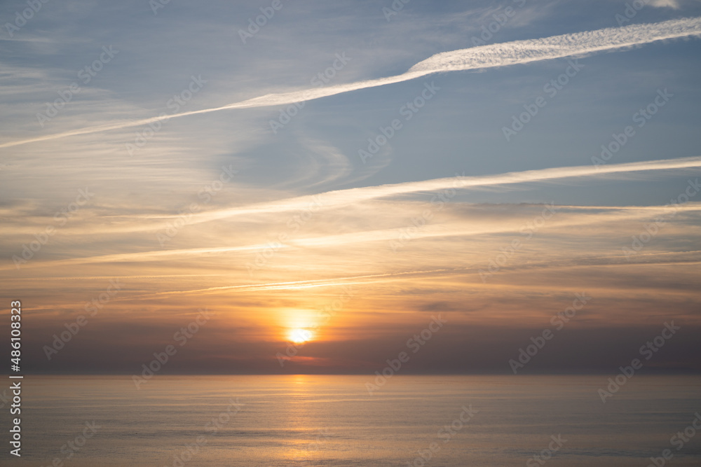 Portugal ocean sunset. Portuguese sky and sea. Pastel sunset with lines from airplanes. Airplane trails on sunset
