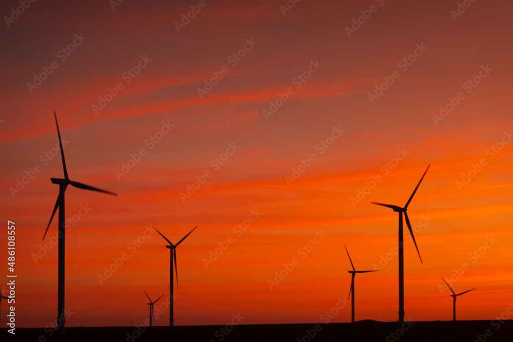Sunset over an eolian wind farm with amazing sky color. Alternative eco energy good for the environment. Renewable energy industry. Sunset over an eolian wind farm with amazing sky color. Alternative eco energy good for the environment. Renewable energy industry.