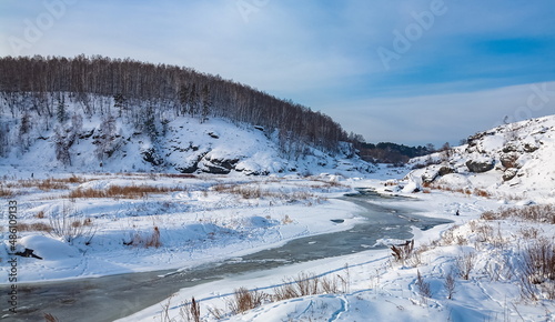 Winter landscape with trees and sky from the high rocky river bank