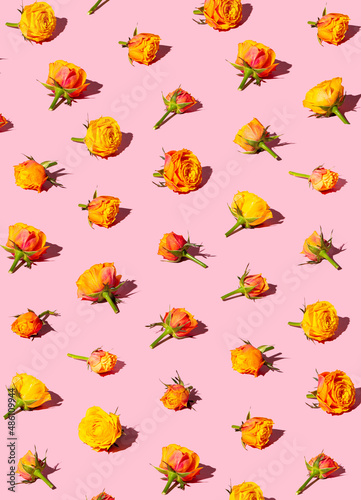 Red and yellow summer flowers on a pink pastel background. MInimal flat lay design.