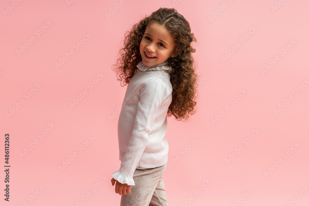 Portrait of little stylish child girl looking at camera with confident expression while posing