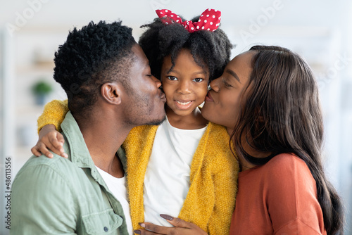 Loving Family. Happy African American Parents Kissing Their Cute Little Daughter